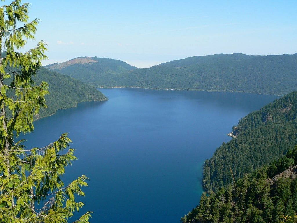 Elevated view overlooking the deep blue waters of Lake Crescent surrounded by forested mountains from the Mount Storm King trail in Olympic National Park.